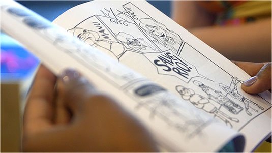 Pessoa folheando uma revistinha Salve Rio!